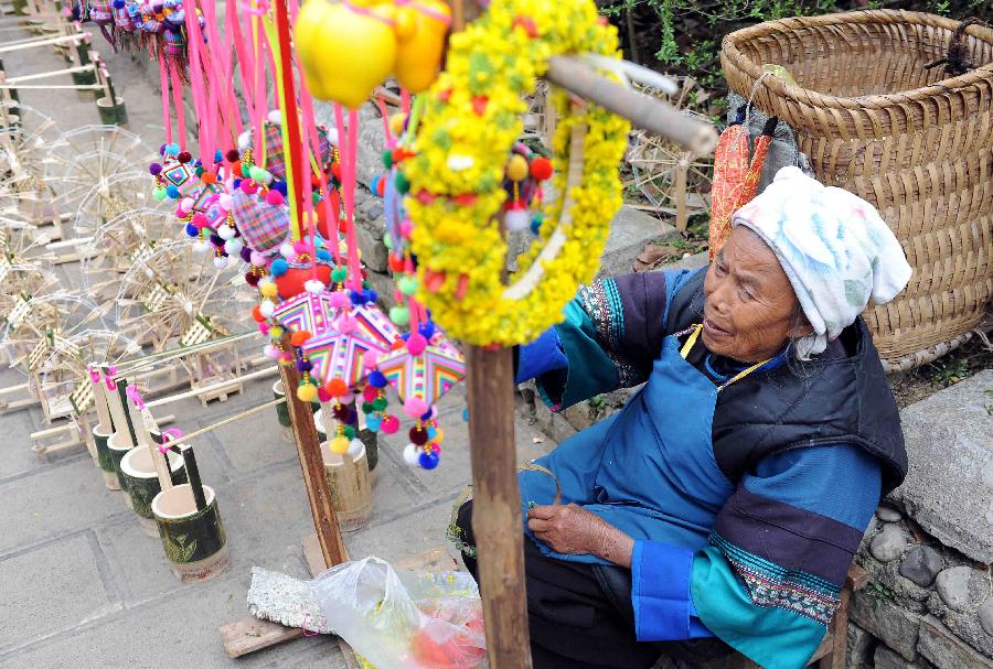 An elder of the Buyi ethnic group sells handicrafts in Luoping County in Qujing City, southwest China's Yunnan Province, Feb. 20, 2013. Luoping County is well-known for its cole flower scenery with its 800,000 mu (53,333 hectares) of cropland planted with cole. In 2012, the county saw its cole flowers industry bring more than one billion yuan (about 16 million US dollars) of revenues. (Xinhua/Yang Zongyou)