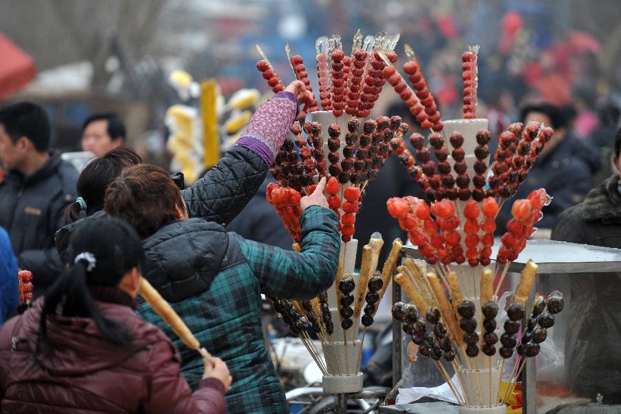 Visitors buy sugar coated haws as they attend a temple fair to celebrate the Lantern Festival in Baoding City, north China's Hebei Province, Feb. 24, 2013. Chinese people received the Lantern Festival on Feb. 24, the 15th day of the first lunar month this year.(Xinhua/Zhu Xudong)