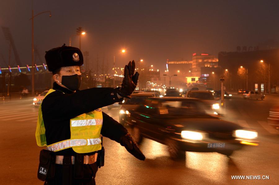 A policeman wearing masks directs traffic in fog-shrouded Jinan, capital of east China's Shandong Province, Feb. 25, 2013. Provincial meteorological authorities issued an orange fog alert on Monday morning. (Xinhua/Guo Xulei) 