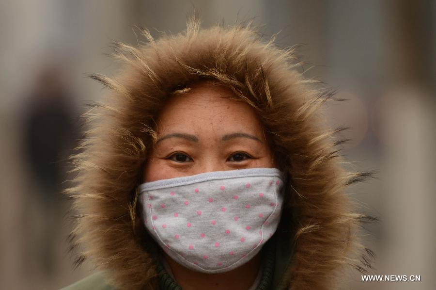 A woman wears masks in fog-shrouded Jinan, capital of east China's Shandong Province, Feb. 25, 2013. Provincial meteorological authorities issued an orange fog alert on Monday morning. (Xinhua/Guo Xulei) 