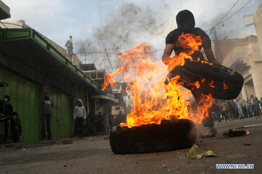 A Palestinian protester burns tires during clashes with Israeli soldiers in the West Bank city of Hebron on Feb. 25, 2013, following the funeral of Palestinian prisoner Arafat Jaradat who died Saturday in Israel's Majeddo prison. (Xinhua/Mamoun Wazwaz) 