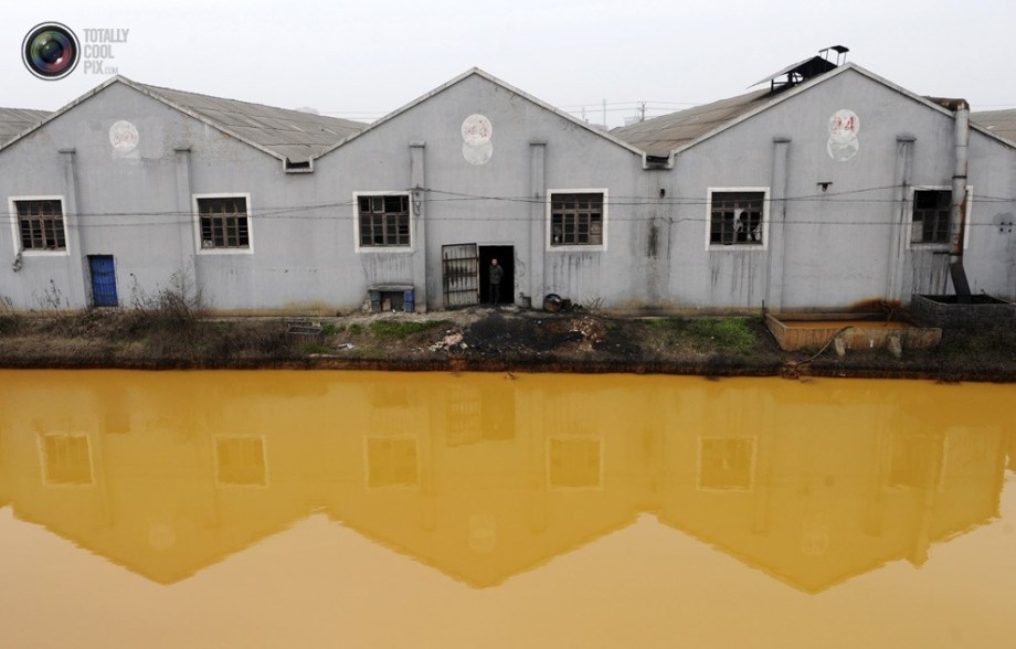 A worker stands beside a polluted river. (File Photo)