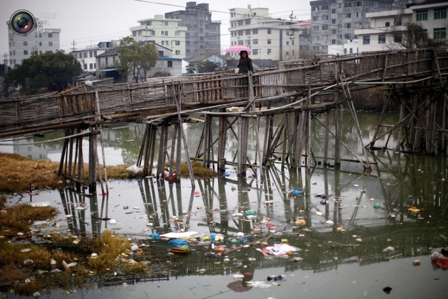 A woman walks across a bridge; the river under the bridge was severely polluted. (File Photo)