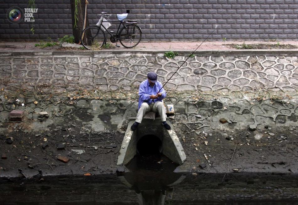 Fishermen fish in a polluted river in Beijing. (File Photo)