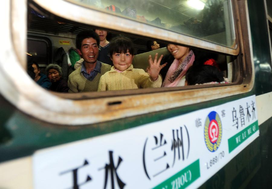 Migrant workers wave to their relatives on a train to Urumqi, capital of northwest China's Xinjiang Uygur Autonomous Region, at Longxi Railway Station in Longxi County, northwest China's Gansu Province, Feb. 26, 2013. Many migrant workers started their journey to work away home after the Chinese Spring Festival holidays. (Xinhua/Nie Jianjiang)