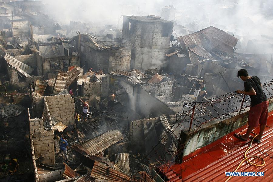 Residents return to their burnt homes after a fire hit a residential area in Valenzuela City, the Philippines, Feb. 27, 2013. More than 400 shanty houses were destroyed by the fire, leaving 500 families homeless. (Xinhua/Rouelle Umali) 