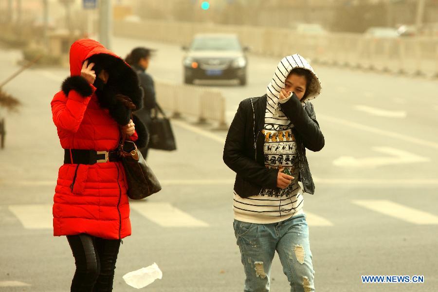 Pedestrians walk in strong wind in Beijing, capital of China, Feb. 28, 2013. Beijing was hit by heavy fog on Thursday morning. The fog led to reduced visibility and degenerated air quality. The city also issued high wind and haze alerts on the same day. (Xinhua/Xu Zijian)