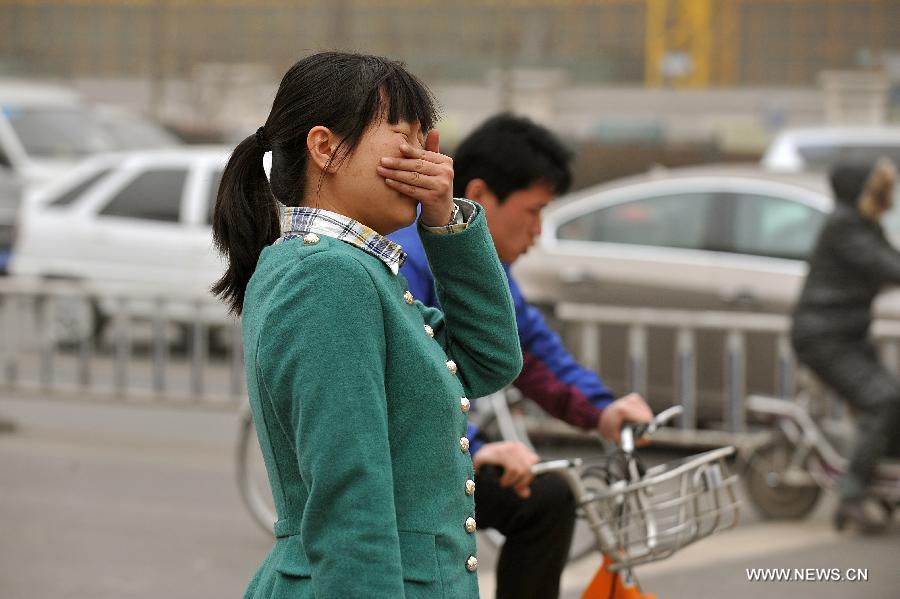 A woman covers her nose and mouth as she walks in a hazy day in Taiyuan, capital of north China's Shanxi Province, Feb. 28, 2013. Pollution worsened in China's north and east provinces as a sand storm hit the region on Thursday. (Xinhua/Zhan Yan)