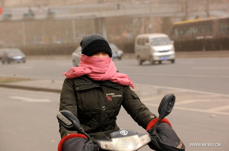 A citizen who has face wrapped up as she rides a motorcycle amid dust and sand in Beijing, capital of China, Feb. 28, 2013. A cold front blew away fog and smog which hit Beijing on Feb. 28 morning, but brought dust and sand from Mongolia and north China's Inner Mongolia Autonomous Region. (Xinhua/He Junchang)