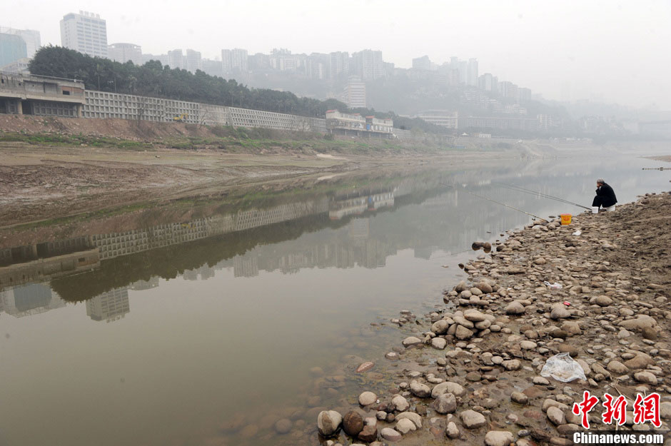 A resident sits and gazes out over the dry riverbed on Feb.25. (Photo/Chinanews.com)
