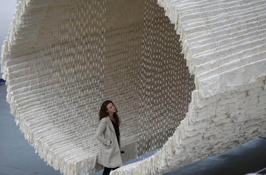 A working staff watches the monumental rice paper boat by renowned Chinese artist Zhu Jinshi during the media preview of the Art 13 London new modern and contemporary art fair at Olympia Grand Hall in London, Feb. 28, 2013. The 12-metre-long installation made of 8,000 sheets of rice paper and presented by Pearl lam Galleries was built by 20 people over three days and brought to London from Shanghai. (Xinhua/Yin Gang)