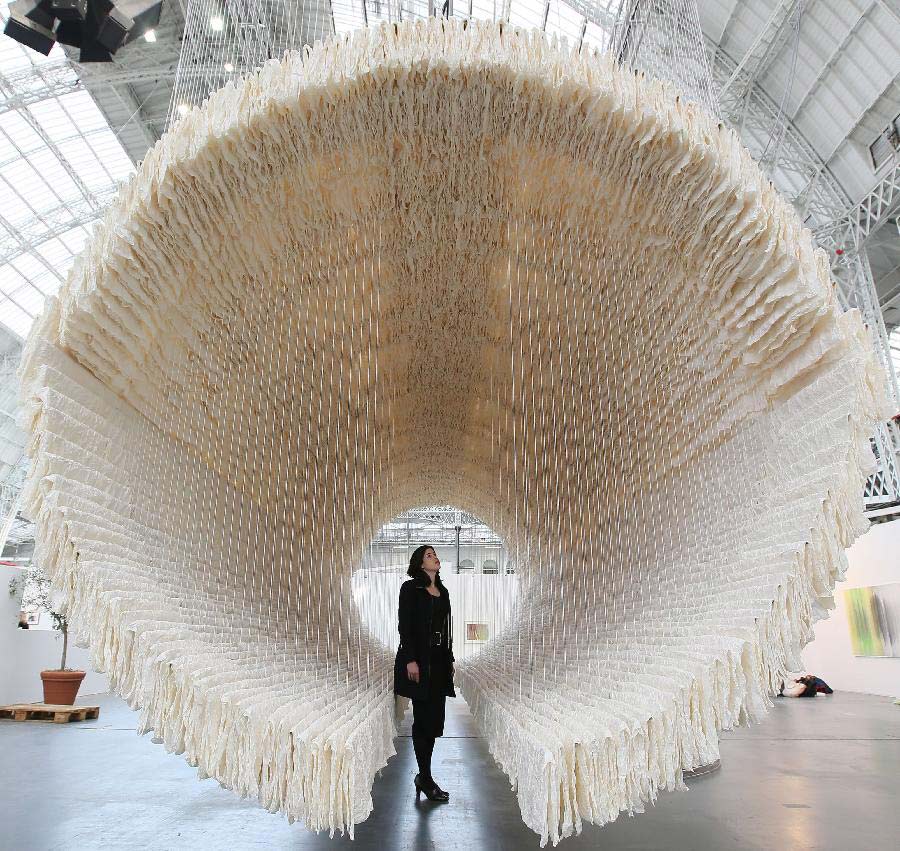 A working staff watches the monumental rice paper boat by renowned Chinese artist Zhu Jinshi during the media preview of the Art 13 London new modern and contemporary art fair at Olympia Grand Hall in London, Feb. 28, 2013. The 12-metre-long installation made of 8,000 sheets of rice paper and presented by Pearl lam Galleries was built by 20 people over three days and brought to London from Shanghai. (Xinhua/Yin Gang)