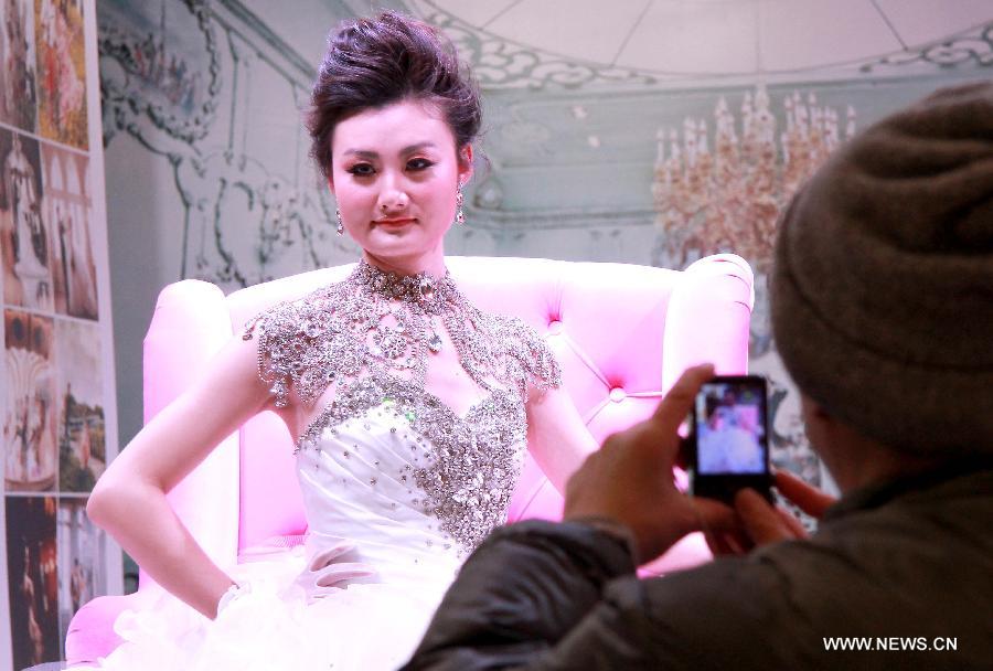 A visitor takes photos of a model wearing wedding dress during a wedding expo in Suzhou City, east China's Jiangsu Province, March 1, 2013. (Xinhua/Hang Xingwei)