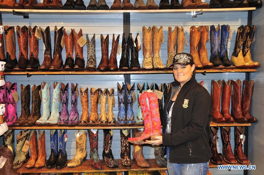 A woman shows some cowboy boots in Houston, the United States, Feb. 28, 2013. Houston Live Stock Show and Rodeo is held during Feb. 25 to March 17 in Reliant Park in Houston, which is a city of rodeo culture. The rodeo was held yearly since 1932, and has become the biggest rodeo in the world. (Xinhua/Zhang Yongxing) 