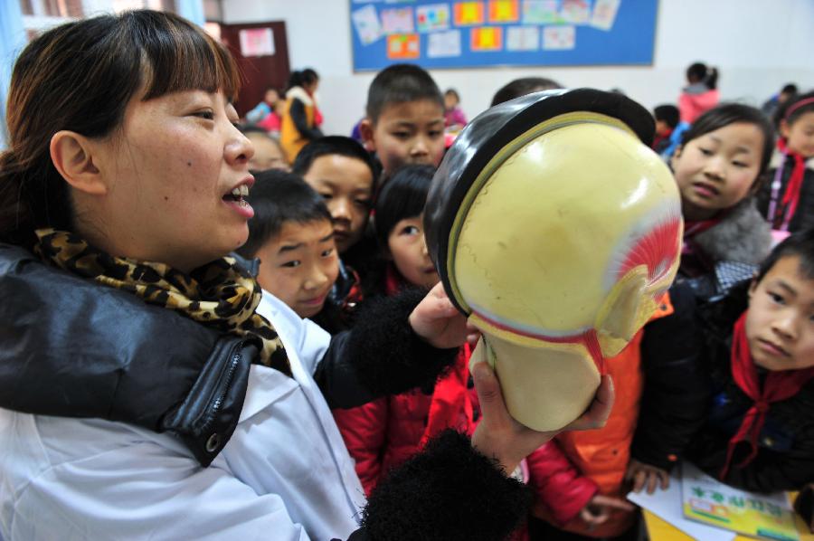 A medical volunteer introduces the general knowledge of ears to the students during an activity celebrating the upcoming Ear-care Day, which falls on March 3 every year, at a primary school in Zigui County, central China's Hubei Province, March 1, 2013. (Xinhua/Wang Huifu)