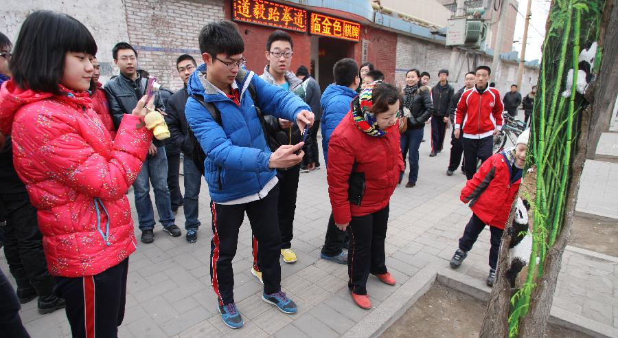 Citizens take photos of tree hollow paintings created by Wang Yue, a local college student, at Jiuzhong Street in Shijiazhuang, capital of north China's Hebei Province, March 1, 2013. (Xinhua/Ding Lixin)