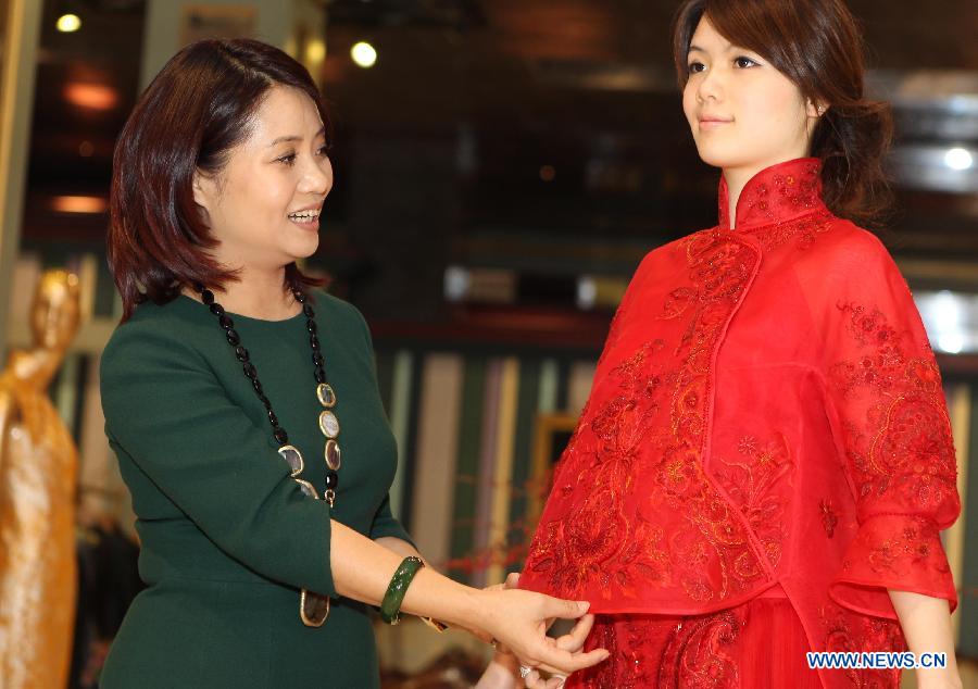 Designer Guo Pei (L) introduces a Chinese-style wedding dress at her store in No. 22 Waitan in Shanghai, east China, March 2, 2013. A wedding dress show was held by Guo Pei, the owner of the flagship store "Chinese Bride" and also a prominent designer who has created ceremonial dresses for both the CCTV Spring Festival Gala and the 2008 Beijing Olympics. (Xinhua/Zhang Ming)