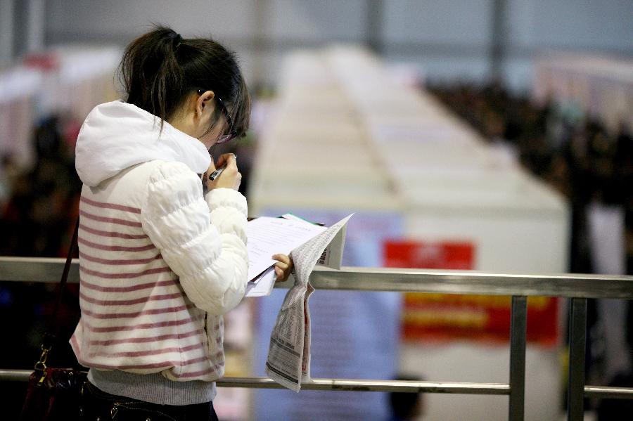 A job seeker reads employment information at a job fair in Nanjing, capital of east China's Jiangsu Province, March 2, 2013. More than 20,000 job opportunities were offered at the job fair. (Xinhua/Wang Xin)