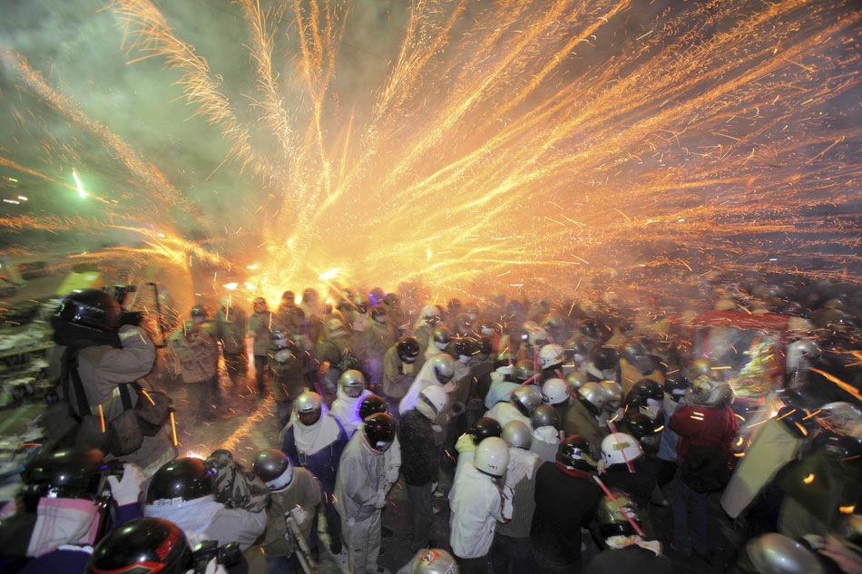 People wearing protective clothes rush into firecracks to get the thrill in Tainan of Taiwan on Feb. 24, 2013. It is local custom in celebration of the Lantern Festival. (Photo/Xinhua)
