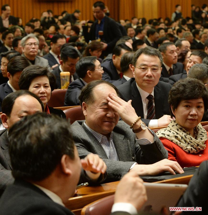 Mo Yan (C), a member of the 12th National Committee of the Chinese People's Political Consultative Conference (CPPCC), gestures while talking with another CPPCC member prior to the opening meeting of the first session of the 12th CPPCC National Committee at the Great Hall of the People in Beijing, capital of China, March 3, 2013. The first session of the 12th CPPCC National Committee opened on March 3. (Xinhua/Wang Jianhua)