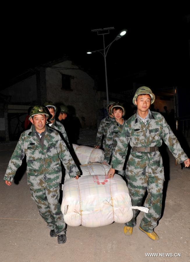 Rescuers carry bedquilts as they are going to distribute them to earthquake-affected residents after a 5.5-magnitude earthquake in Eryuan County of Dali Bai Autonomous Prefecture, southwest China's Yunnan Province, on March 3, 2013. The number of people confirmed injured by a 5.5-magnitude earthquake that hit southwest China's Yunnan Province on Sunday afternoon has risen to 30, local authorities have said. (Xinhua/Lin Yiguang)