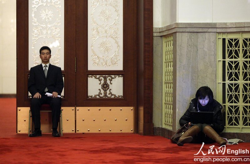 A journalist writes reporting at the Great Hall of the People. (Photo/People's Daily Online)