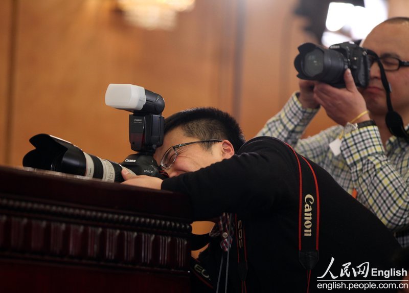 A journalist takes photos at a press conference of the first session of the 12th CPPCC National Committee.(Photo/People's Daily Online)
