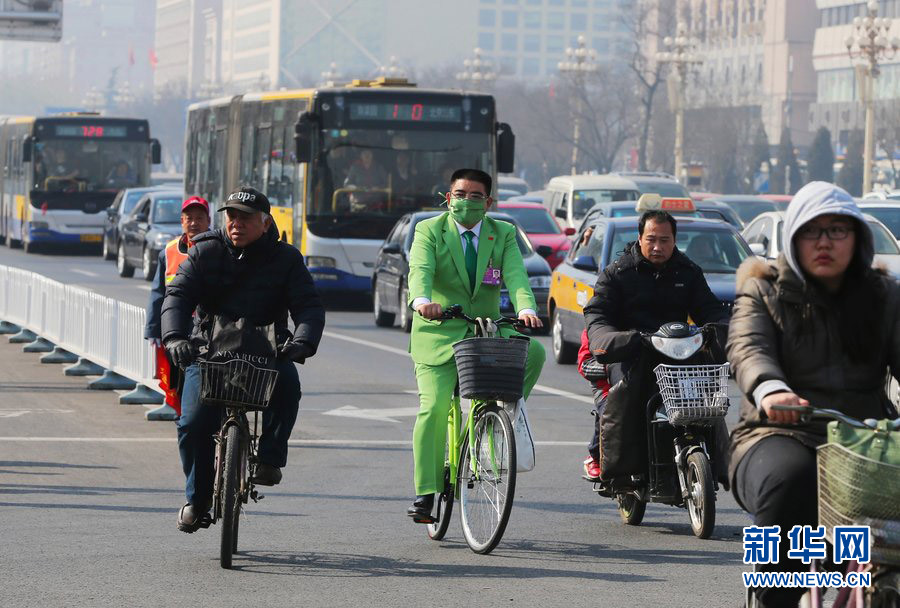 Chen Guangbiao, wearing green suit and green breathing mask, rides a green bicycle to attend the first session of the 12th CPPCC National Committee on March 3, 2013.  (Photo/Xinhua)
