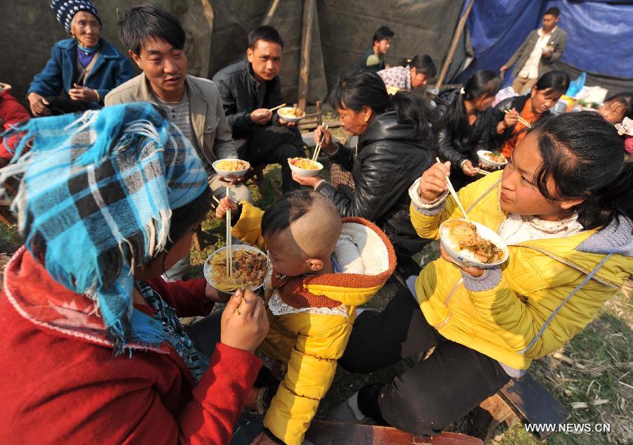 People have meals at Qiandian Village of Liantie Township in Eryuan County of Dali Bai Autonomous Prefecture, southwest China's Yunnan Province, March 4, 2013. A 5.5-magnitude earthquake hit Eryuan County on March 3. Thirty people have been confirmed injured, while some 21,000 people have been evacuated. (Xinhua/Lin Yiguang) 