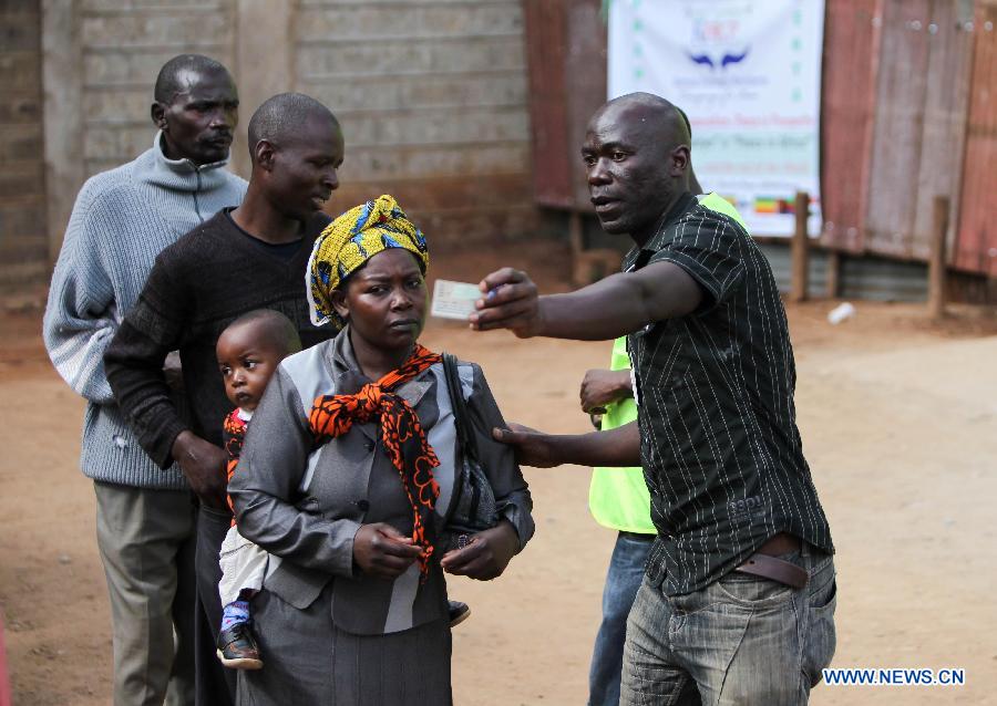 An election staff (R) guides voters at a polling station in Nairobi, Kenya, March 4, 2013. A total of 14.3 million Kenyan voters lined up to cast their ballots Monday morning to choose the country's next president, the first after disputed presidential elections tally stirred up violence five years ago. (Xinhua/Meng Chenguang) 