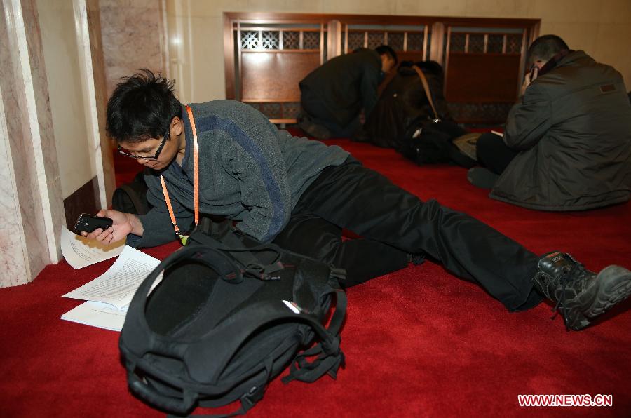A journalists reads conference materials on the floor of the Great Hall of the People in Beijing, capital of China, March 5, 2013. The first session of the 12th National People's Congress (NPC) will open here on March 5. (Xinhua/Chen Jianli)