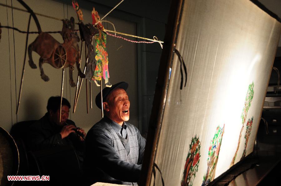 A folk artist presents Daoqing (a folk operetta originated from the chanting of Taoist scriptures) shadow play backstage in Huanxian County, northwest China's Gansu Province, late March 4, 2013. The county has made great efforts to preserve and promote the folk performing art in recent years. Huanxian now boasts 52 shadow play troupes. (Xinhua/Fan Peishen) 