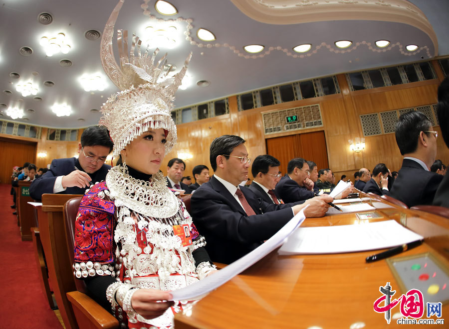 A female ethnic minority deputy wearing a traditional ethnic minority costume carefully listens the government work report during the opening meeting of the first session of the 12th National People's Congress (NPC) at the Great Hall of the People in Beijing, capital of China, March 5, 2013. (China Pictorial/Xu Xun)