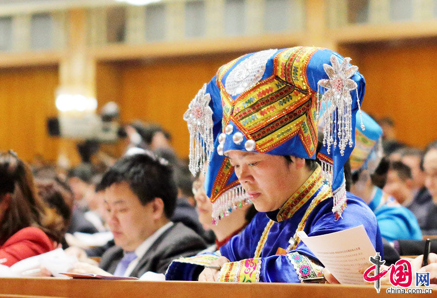 A female ethnic minority deputy wearing a traditional ethnic minority costume carefully listens the government work report during the opening meeting of the first session of the 12th National People's Congress (NPC) at the Great Hall of the People in Beijing, capital of China, March 5, 2013. (China Pictorial/Xu Xun)