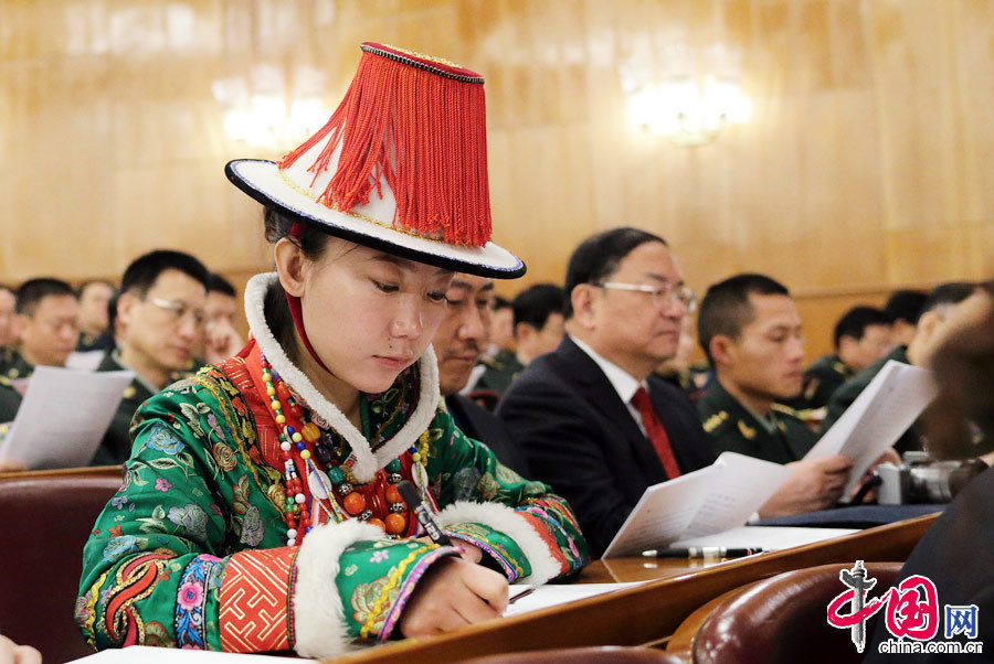 A female ethnic minority deputy wearing a traditional ethnic minority costume carefully listens the government work report during the opening meeting of the first session of the 12th National People's Congress (NPC) at the Great Hall of the People in Beijing, capital of China, March 5, 2013. (China Pictorial/Xu Xun)