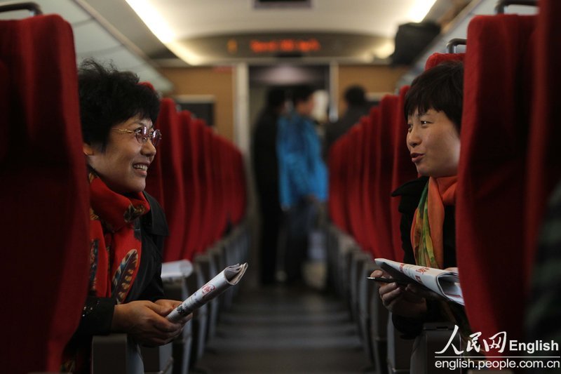 A new NPC Deputy Leng Xuying (R), the principal of No.1 experimental primary school in Guangping County, seeks experiences about how to better perform duties from experienced NPC Deputy Shao Xizhen at training heading to Beijing on March 02, 2013. (Photo/ People's Daily Online)