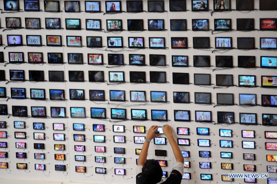 A staff worker fixes the position of a telecommunication gadget at his booth wall during Mega Bazar Computer 2013 at Jakarta Convention Center, Jakarta, Indonesia, March 6, 2013. Indonesian Computer Entrepreneurs Association (Apkomindo) revealed that this year's computer tablet PC market was expected to rise 60 percent by the end of the year. (Xinhua/Veri Sanovri)