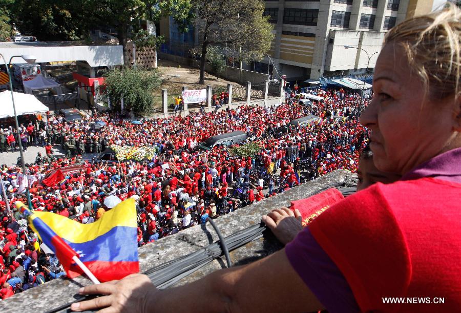 A woman watches as residents participate in the funeral procession in honor of Venezuelan President Hugo Chavez on the streets of Caracas, capital of Venezuela, on March 6, 2013. On Tuesday afternoon, Venezuelan President, Hugo Chavez, died after fighting for almost two years with a cancer disease. The body of Chavez is moved from the health center to the Military Academy in southern Caracas, inside Tiuna's Fort. (Xinhua/Juan Carlos Hernandez)