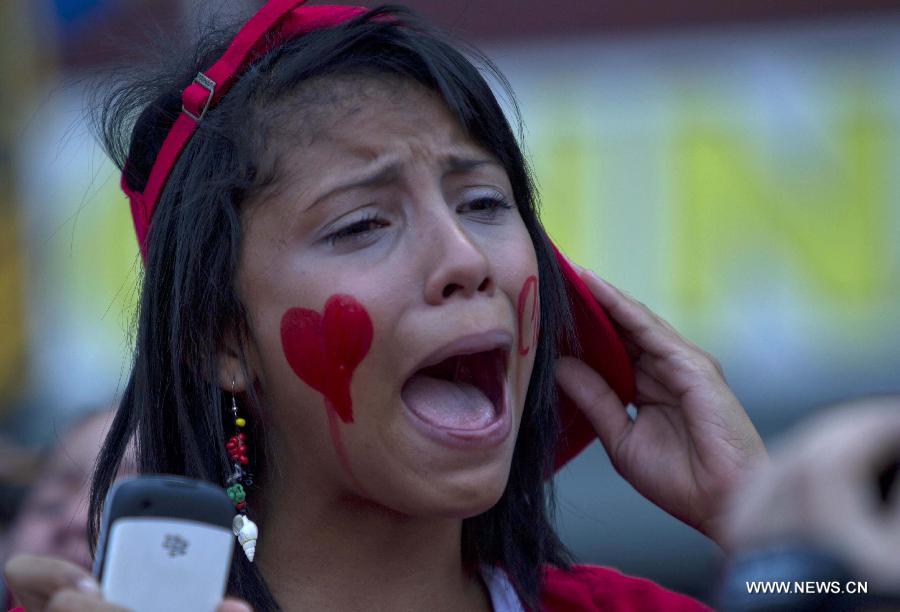 A woman reacts while participating in the funeral procession in honor of Venezuelan President Hugo Chavez on the streets of Caracas city, capital of Venezuela, on March 6, 2013. On Tuesday afternoon, Venezuelan President, Hugo Chavez, died after fighting for almost two years with a cancer disease. The body of Chavez is moved from the health center to the Military Academy in southern Caracas, inside Tiuna's Fort. (Xinhua/David de la Paz)