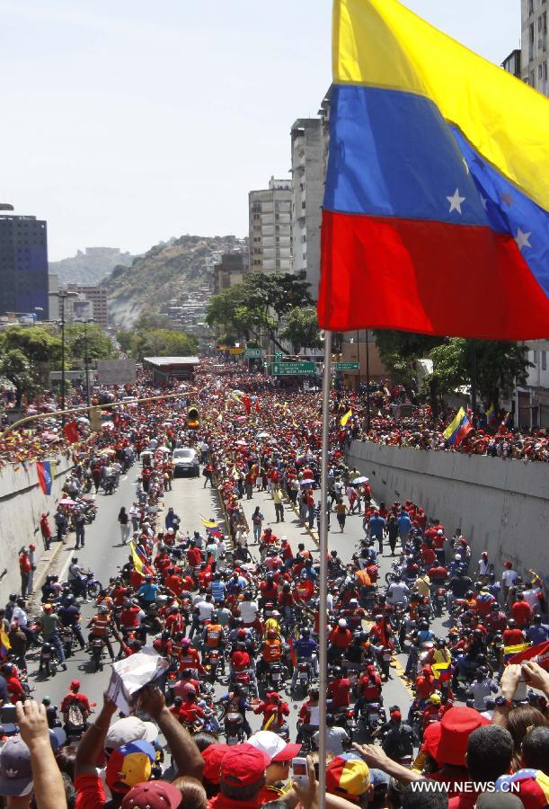 Members of the military escort Venezuelan National Guard hold a security fence during the funeral procession in honor of Venezuelan President Hugo Chavez on the streets of Caracas, capital of Venezuela, on March 6, 2013. On Tuesday afternoon, Venezuelan President, Hugo Chavez, died after fighting for almost two years with a cancer disease. The body of Chavez is moved from the health center to the Military Academy in southern Caracas, inside Tiuna's Fort. (Xinhua/Juan Carlos Hernandez)