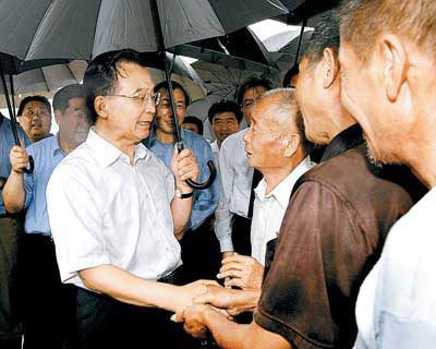 Wen Jiabao shakes hands with flood victims in Wangjiaba, east China's Anhui Province on July 13, 2007.(Xinhua File Photo)