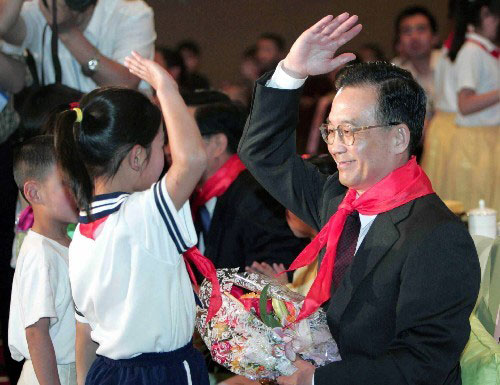 Wen Jiabao greets children with the Young Pioneer's salute ahead of Children's Day on May 29, 2004. (Xinhua File Photo)