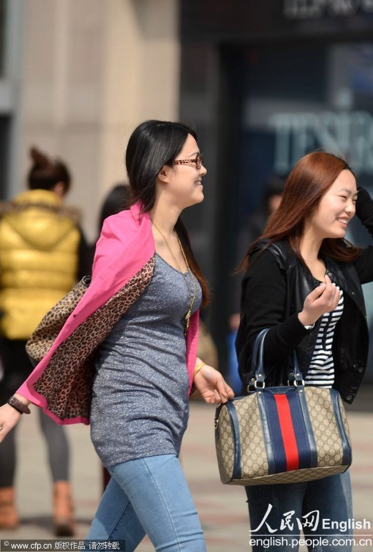 Pedestrians wear spring and even summer clothes on the street of Yangzhou on Mar. 6, 2013. The temperature reached 22 degrees Celsius (Photo/Xinhua)