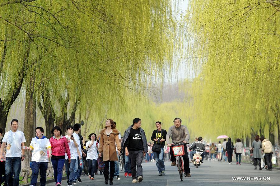 Tourists walk on the Bai Causeway along the West Lake on an early spring day in Hangzhou, capital of east China's Zhejiang Province, March 7, 2013. (Xinhua/Ju Huanzong)