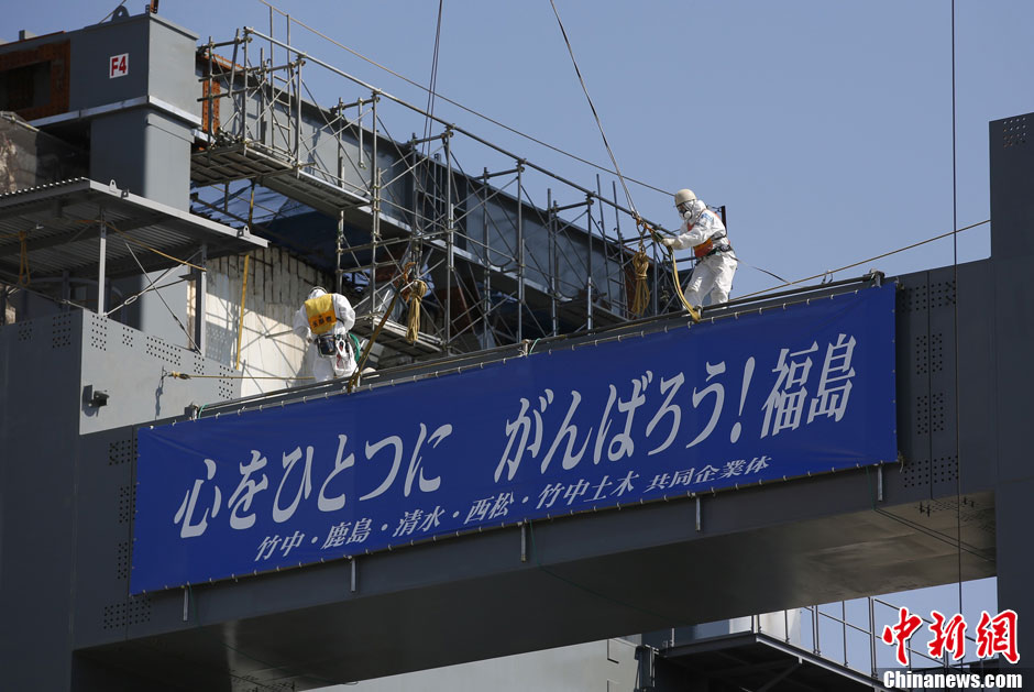 Workers stand near the multi-nuclide removal facility being constructed at Tokyo Electric Power Co.'s tsunami-crippled Fukushima Dai-ichi nuclear power plant in Okuma, Fukushima prefecture, Wednesday, March 6, 2013, ahead of the second anniversary of the March 11 earthquake and tsunami. Some 110,000 people living around the nuclear plant were evacuated after the massive disasters knocked out the plant's power and cooling systems, causing meltdowns in three reactors and spewing radiation into the surrounding air, soil and water. (Chinanews.com)