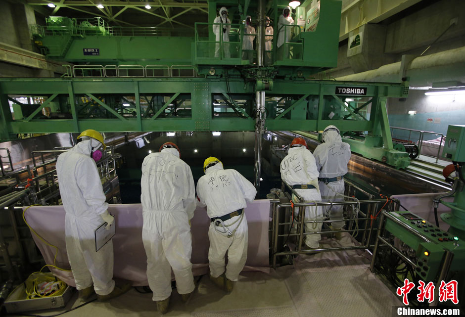 Workers stand near the multi-nuclide removal facility being constructed at Tokyo Electric Power Co.'s tsunami-crippled Fukushima Dai-ichi nuclear power plant in Okuma, Fukushima prefecture, Wednesday, March 6, 2013, ahead of the second anniversary of the March 11 earthquake and tsunami. Some 110,000 people living around the nuclear plant were evacuated after the massive disasters knocked out the plant's power and cooling systems, causing meltdowns in three reactors and spewing radiation into the surrounding air, soil and water. (Chinanews.com)