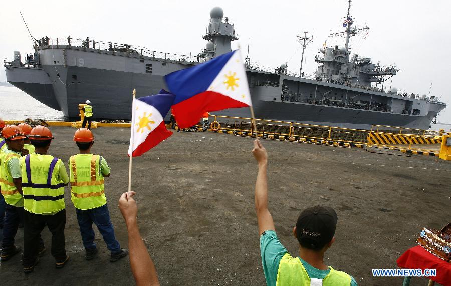 Port workers wave the Philippine flags to welcome the USS Blue Ridge (LCC-19) as it docks in Manila, the Philippines, March 7, 2013. The USS Blue Ridge, flagship for the Commander of the U.S. Navy's 7th Fleet, started a four-day goodwill visit to Manila on Thursday. (Xinhua/Rouelle Umali) 