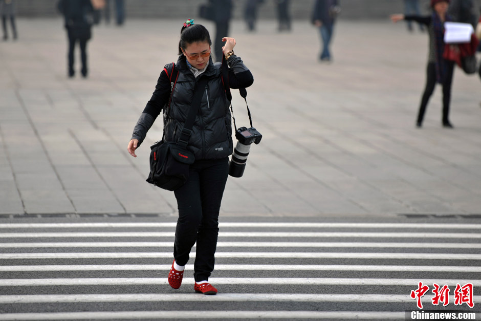 A female journalist covering the NPC and CPPCC sessions walks at Tiananmen Square. (Photo/CNS)