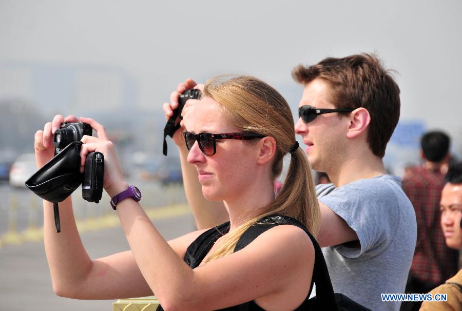 Foreign tourists wearing summer clothing take photos at the Tian'anmen Square in Beijing, capital of China, March 8, 2013. The highest temperature of Beijing hit this year's new high to 19 degrees Celsius on March 8. (Xinhua/Chen Yehua)
