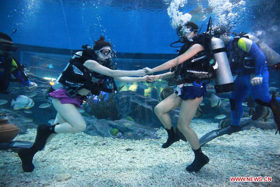 Local citizens Qu Di (L) and Wang Fang dive under professional guidance to enjoy a special Women's Day at the Polar Ocean World of Wuhan, capital of central China's Hubei Province, March 8, 2013. (Xinhua/Wang Zhenwu)